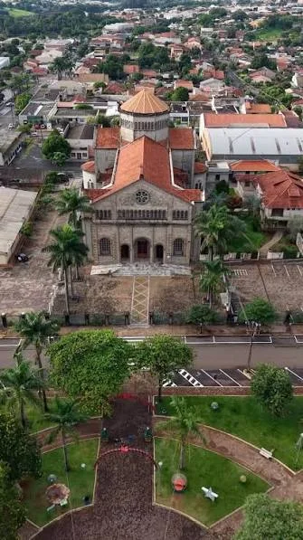 Vista aérea de uma igreja e praça em Ibiporã, Paraná, com a cidade ao fundo