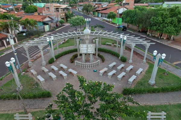 Vista aérea de uma praça em Leópolis, Paraná, com monumento, bancos e jardins