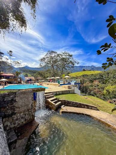Área de lazer com piscinas, queda de água e vegetação